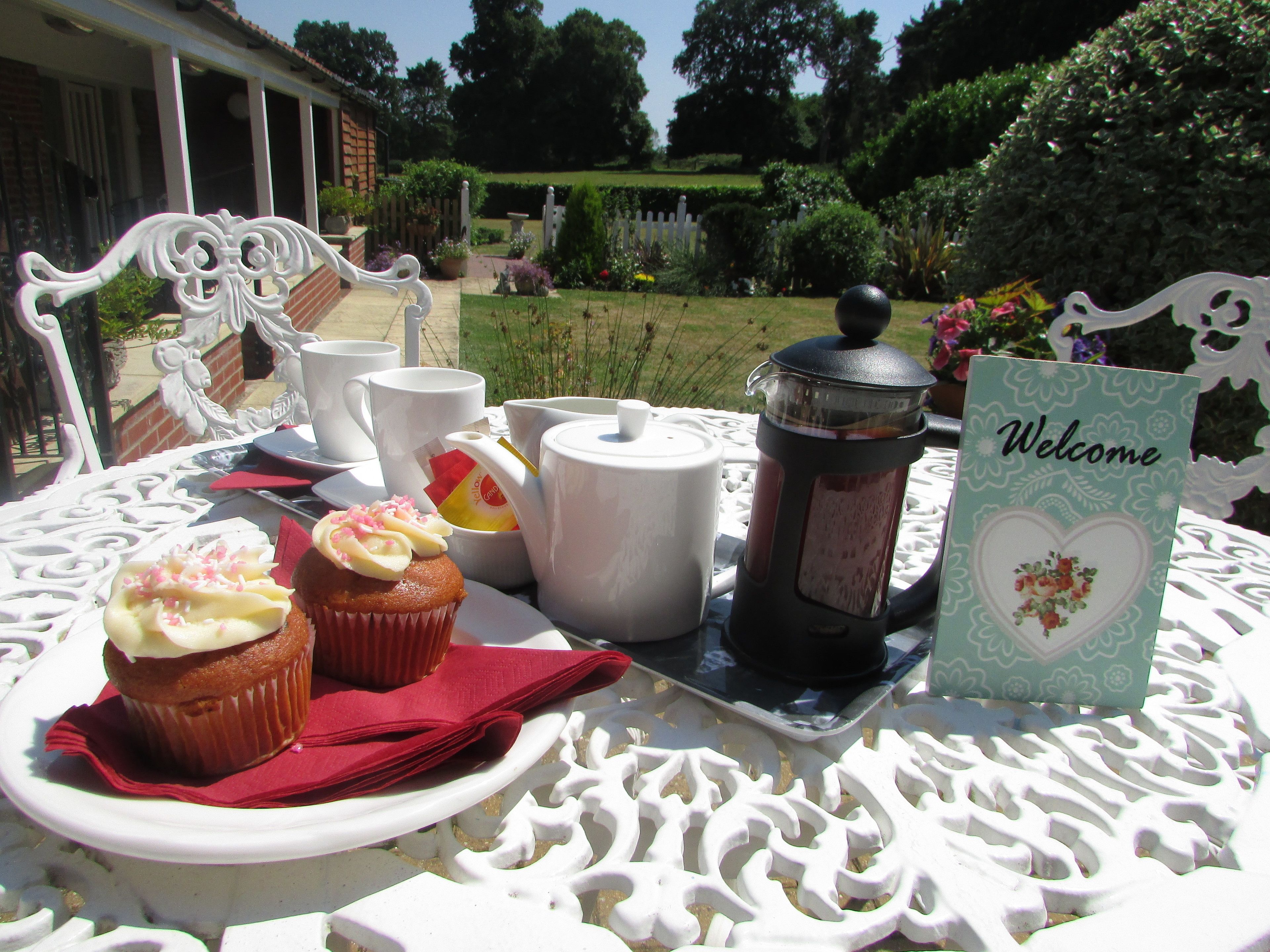 A table set with a teapot, cups, a teapot lid, a muffin, and a 'Welcome' card.
