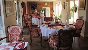 A dining area with tables set for four, surrounded by red upholstered chairs. - Decoy Barn (Great Yarmouth)