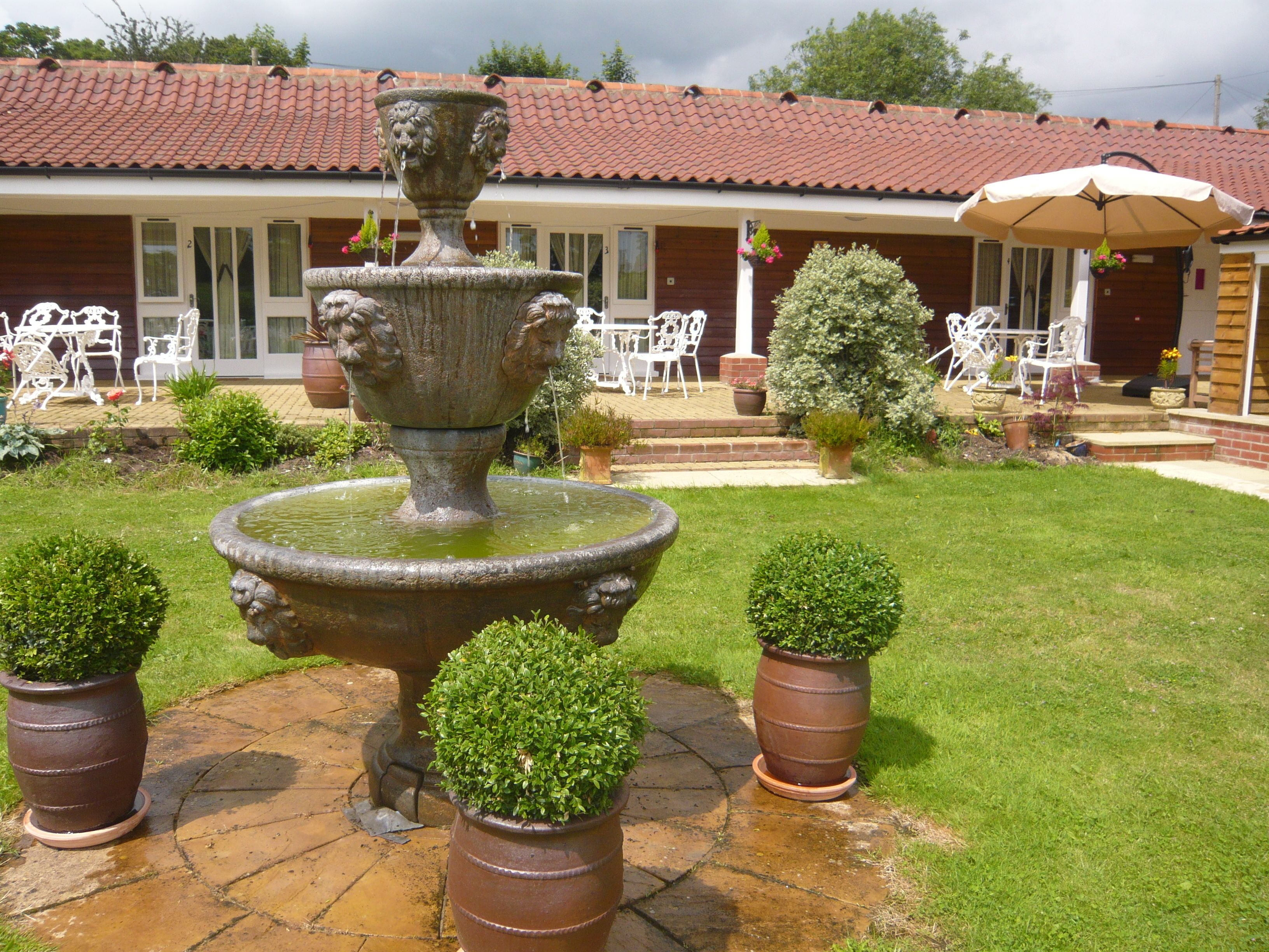 A courtyard with a stone fountain, potted plants, and outdoor furniture.