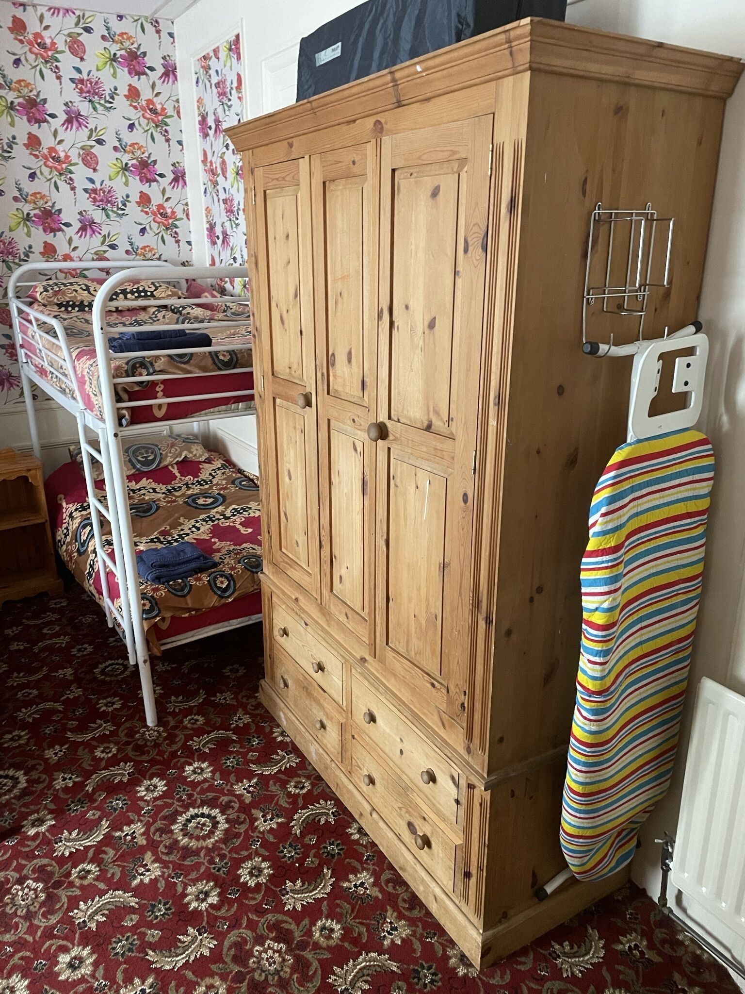 A bedroom with a bunk bed, a wooden wardrobe, and a radiator.