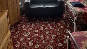 Une pièce avec un canapé en cuir noir, un meuble en bois et un tapis à motifs.