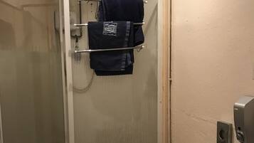 Un baño con ducha de vidrio, inodoro y toallero con toallas.