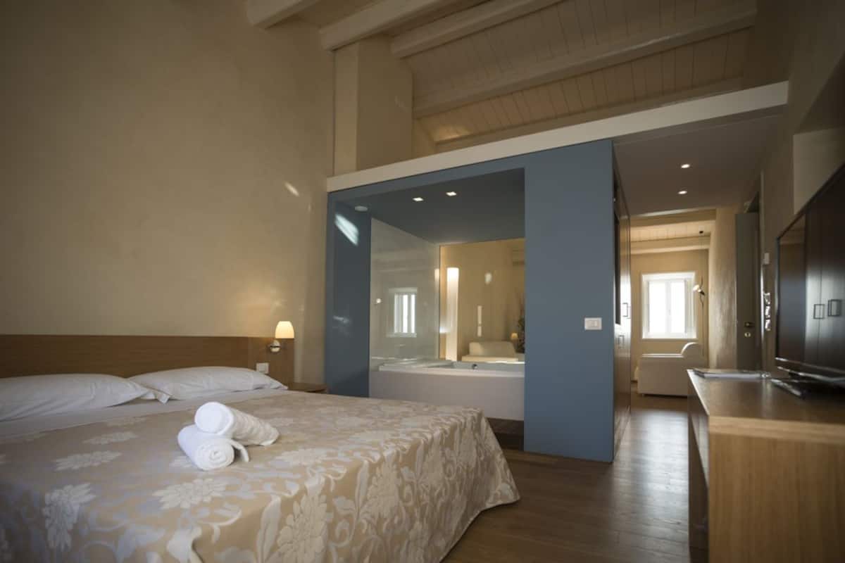 Een hotelkamer met een bed, een badkamer met een bad en een bureau met een televisie.