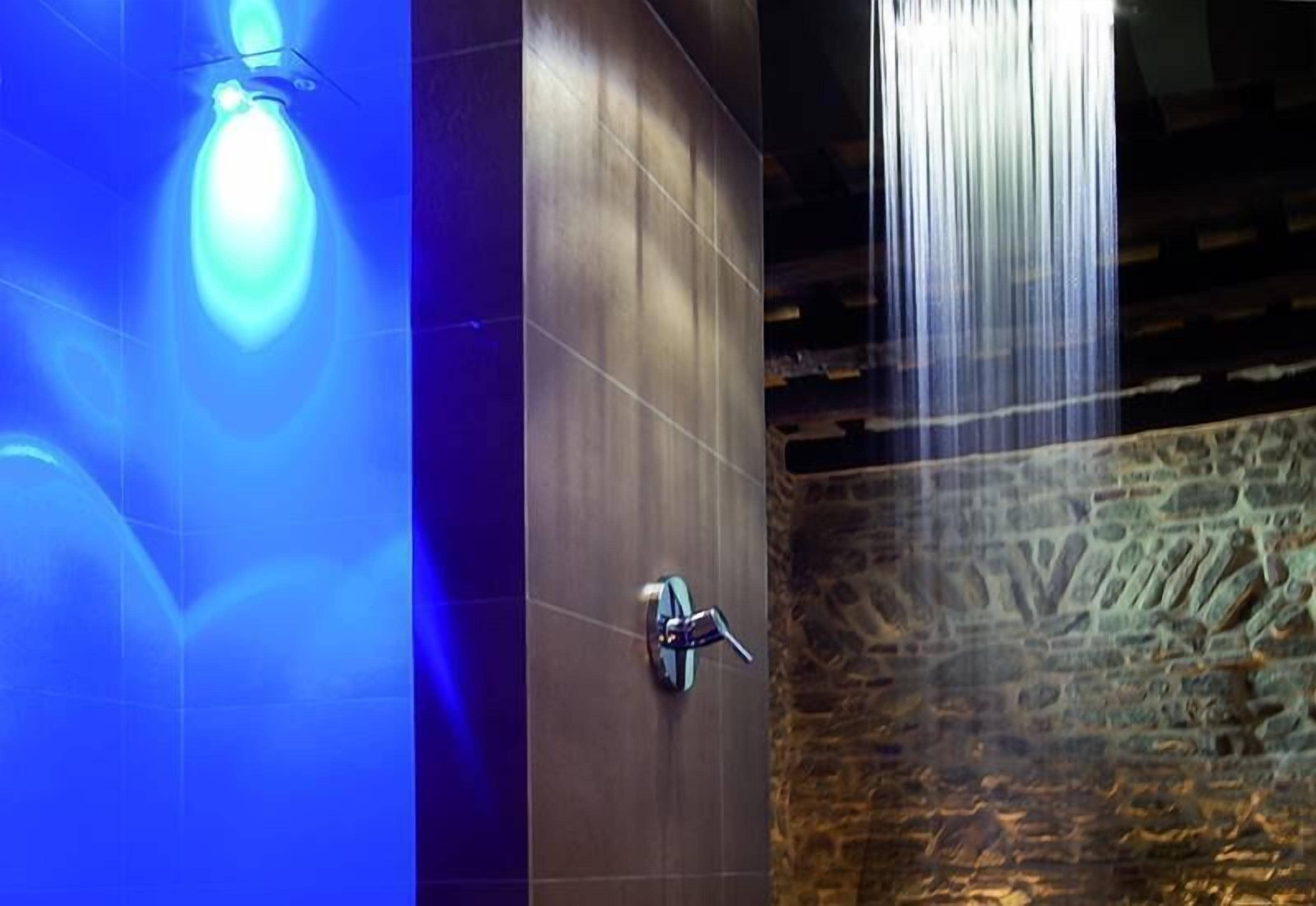Un baño moderno con pared de piedra y lámpara azul.