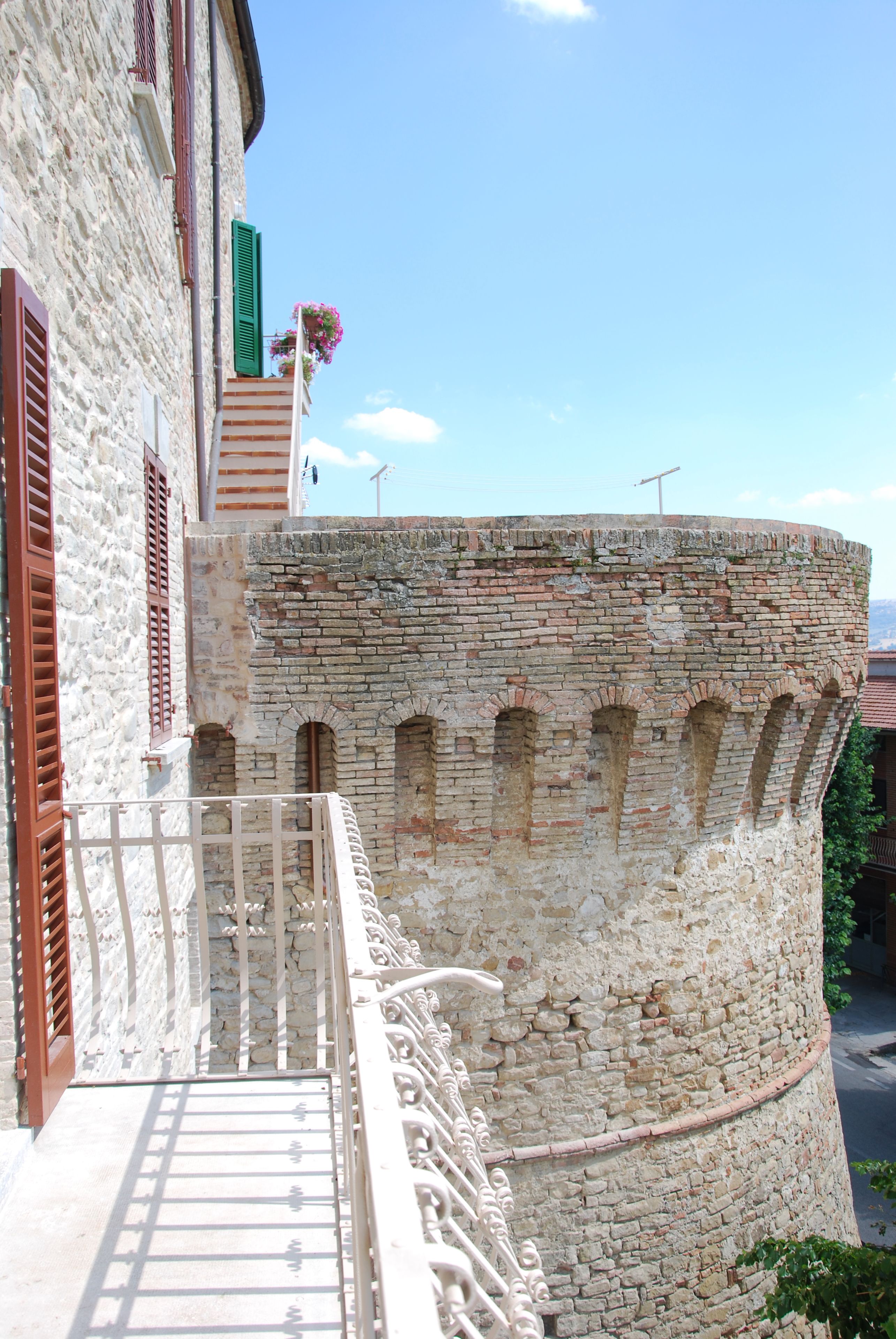 Ein Steinhaus mit Balkon und einem Backsteinturm.