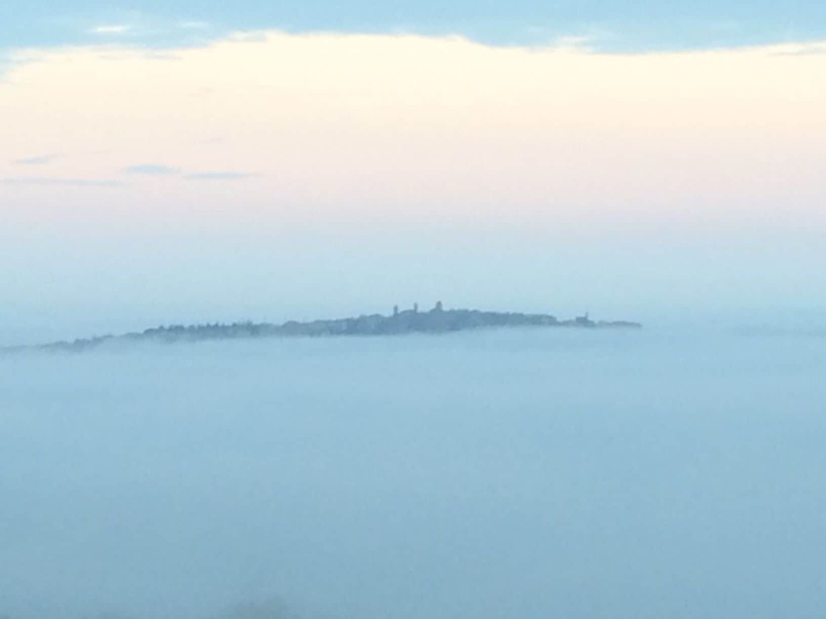 Una vista brumosa de un pueblo costero con edificios delineados contra la niebla.
