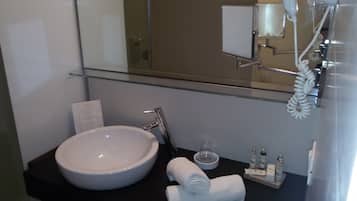 A modern bathroom with a large white sink, a glass shower enclosure, and a towel rack.