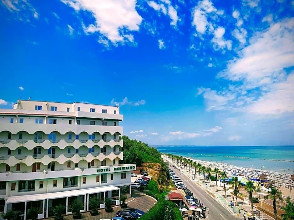 Un hotel dal design moderno, situato vicino a una spiaggia sotto un cielo sereno.