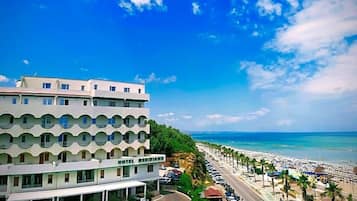 Un hotel dal design moderno, situato vicino a una spiaggia sotto un cielo sereno.