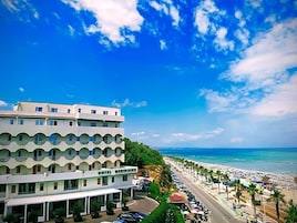 A hotel with a modern design, located near a beach with a clear sky.