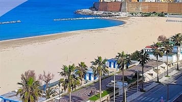 Un hotel sulla costa con vista sulla spiaggia, palme e un cielo azzurro limpido.