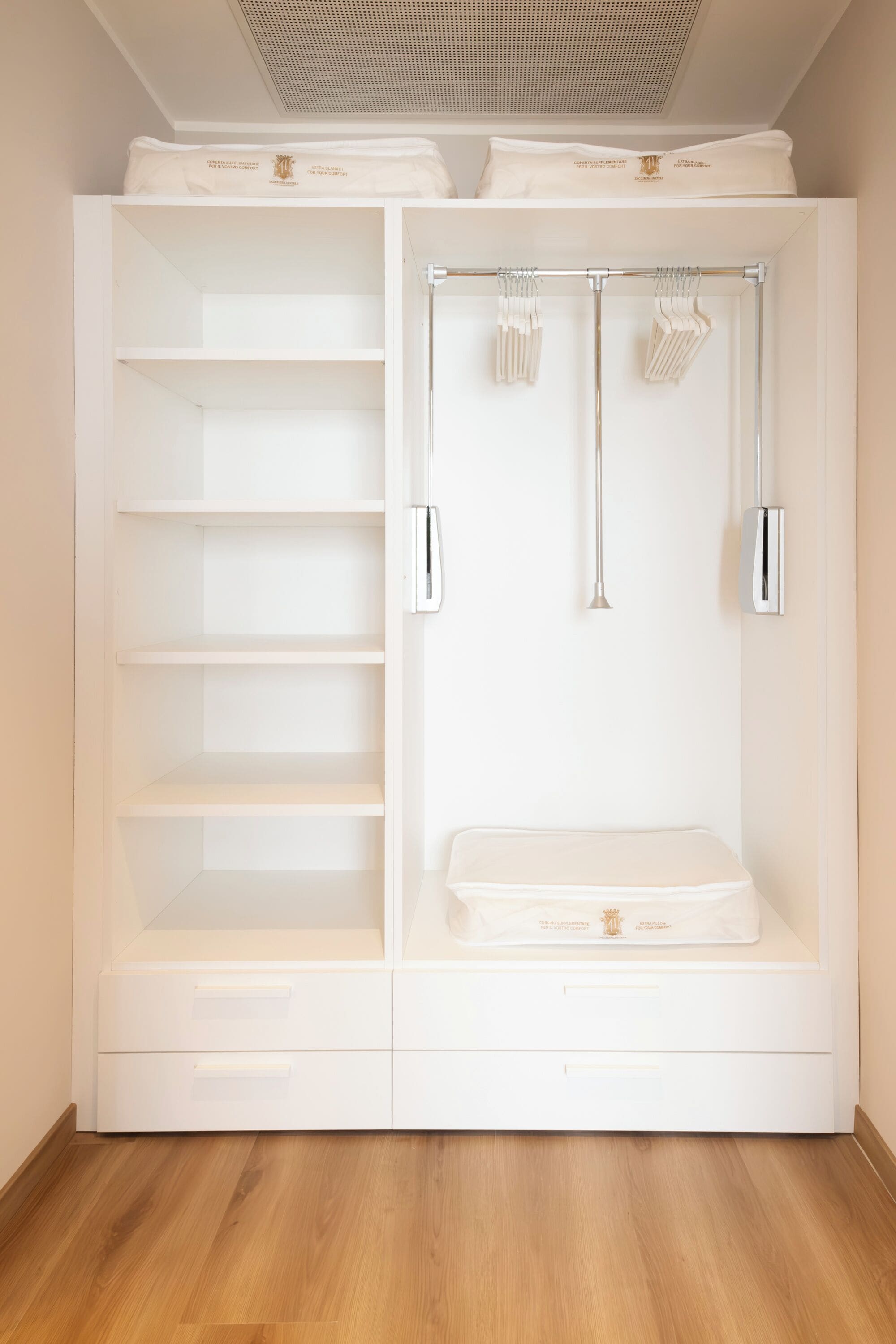 A white walk-in closet with open shelves, a hanging rod, and a flat storage area.