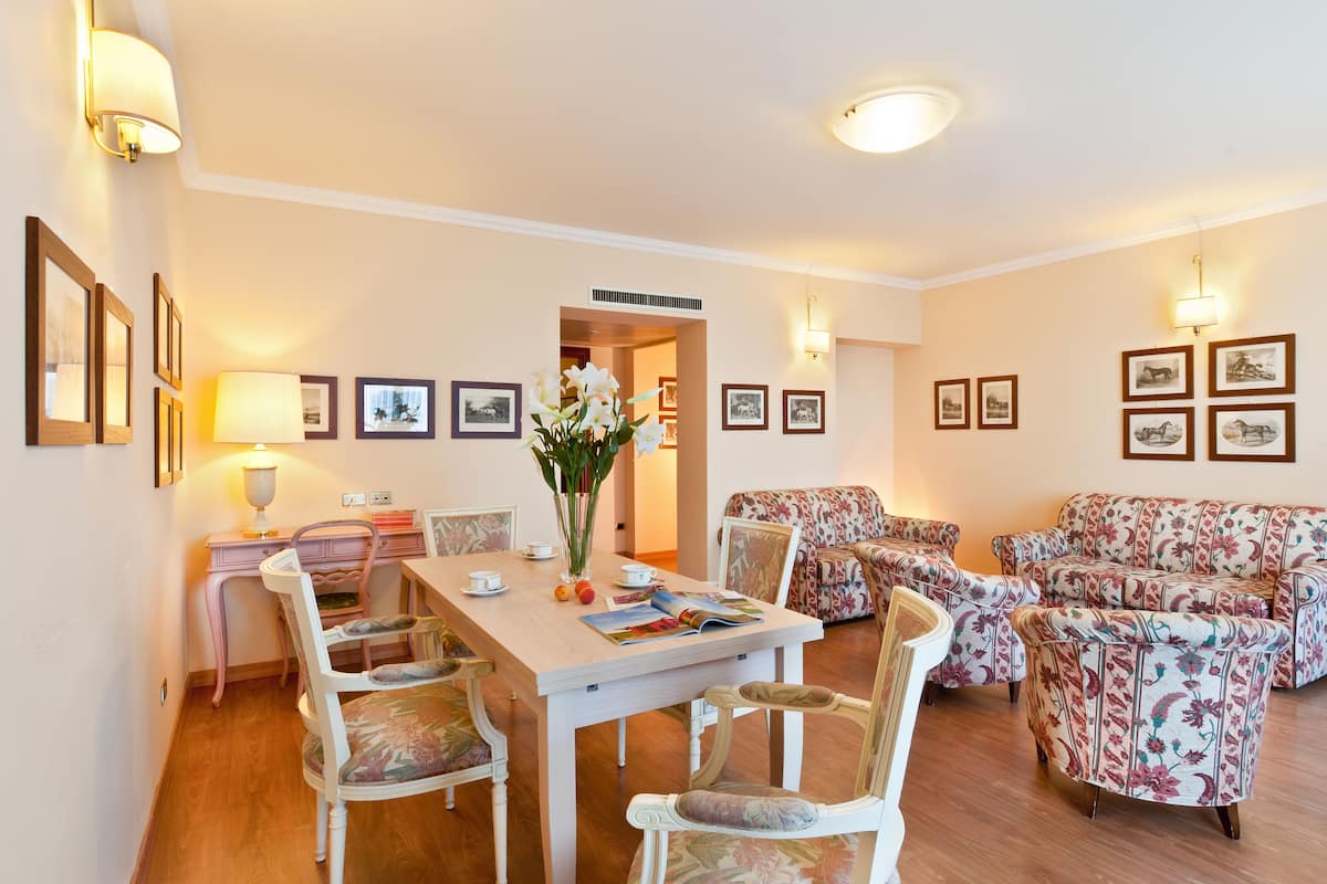 Un comedor con mesa de madera, sillas blancas y un sofá floral.