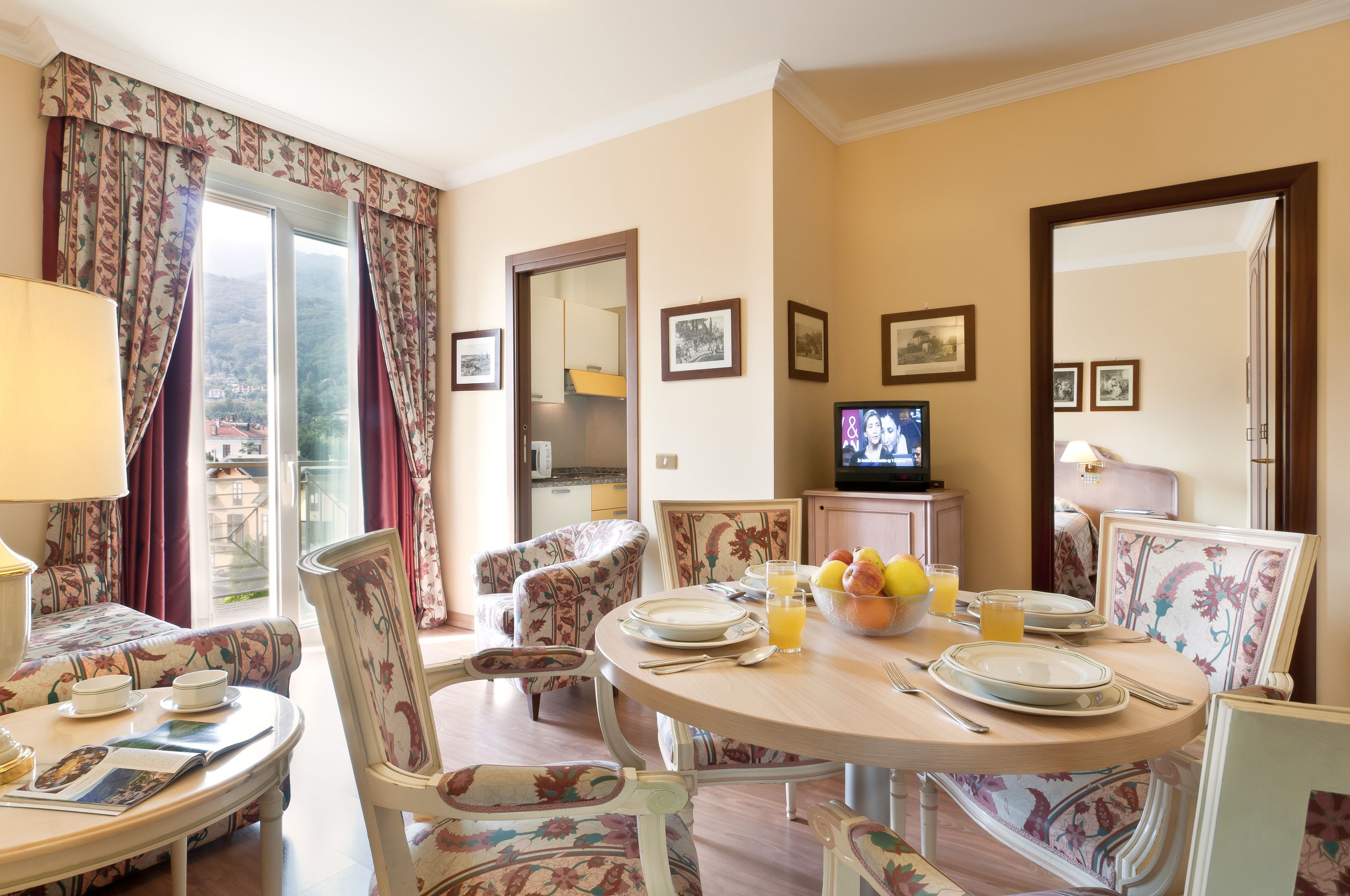 A dining area with floral-patterned chairs and a round table set for breakfast.