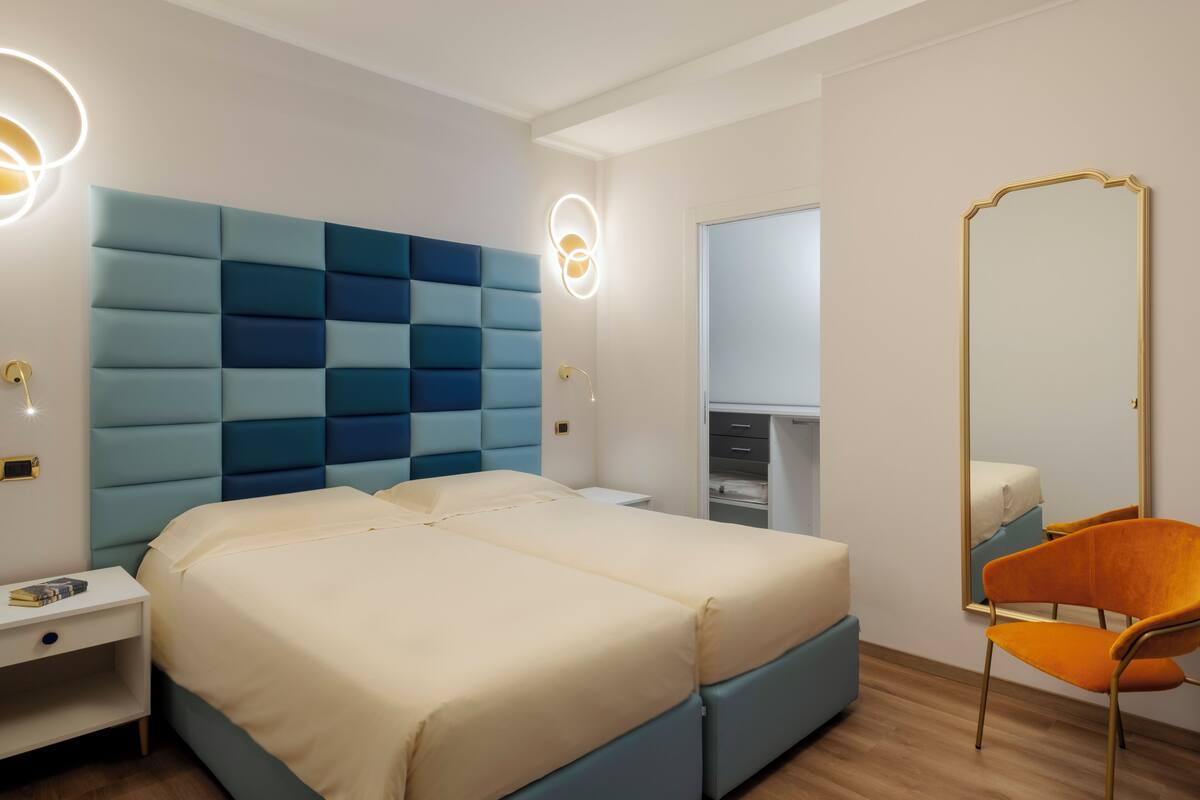 Un dormitorio con una cama grande, una mesita de noche, un aparador, un espejo y una silla.