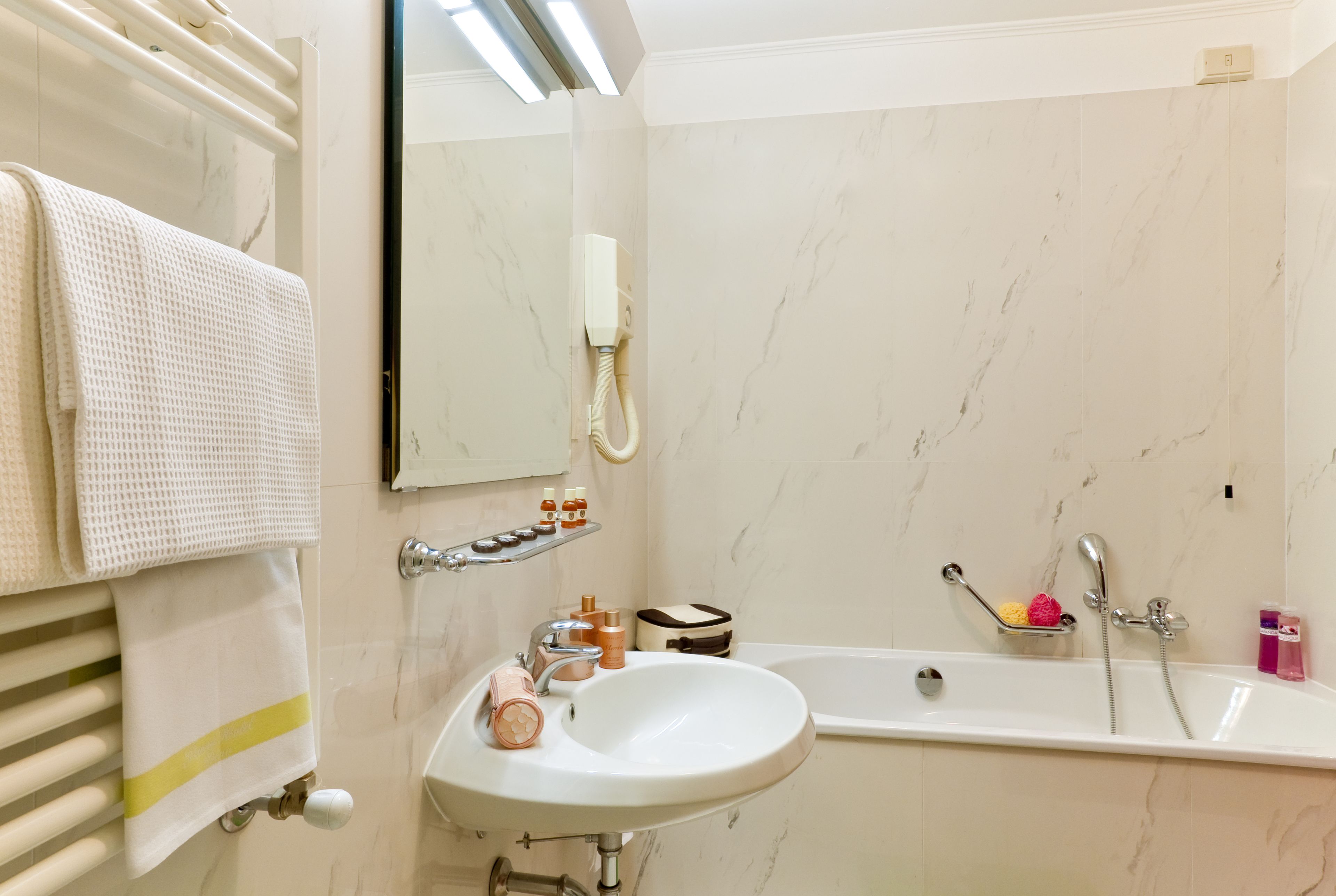 Un baño con lavamanos, espejo, toallero y bañera.