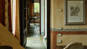 A hallway with a wooden chair, a framed picture on the wall, and a staircase leading to another room. - Tenuta La Cascinetta (Buriasco)