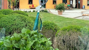 A yellow building with multiple windows and balconies, a clock, and outdoor seating with umbrellas. - Tenuta La Cascinetta (Buriasco)