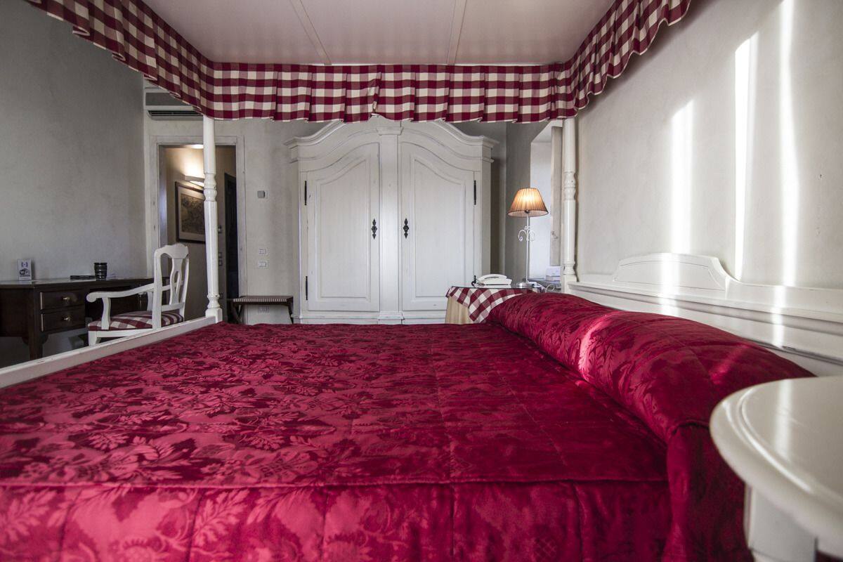 A bedroom with a large bed, a wardrobe, a desk, and a chair.