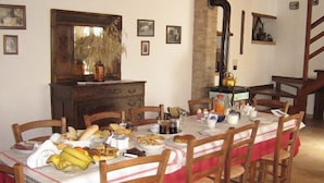 Un comedor con una larga mesa dispuesta para una comida, rodeada de sillas de madera.