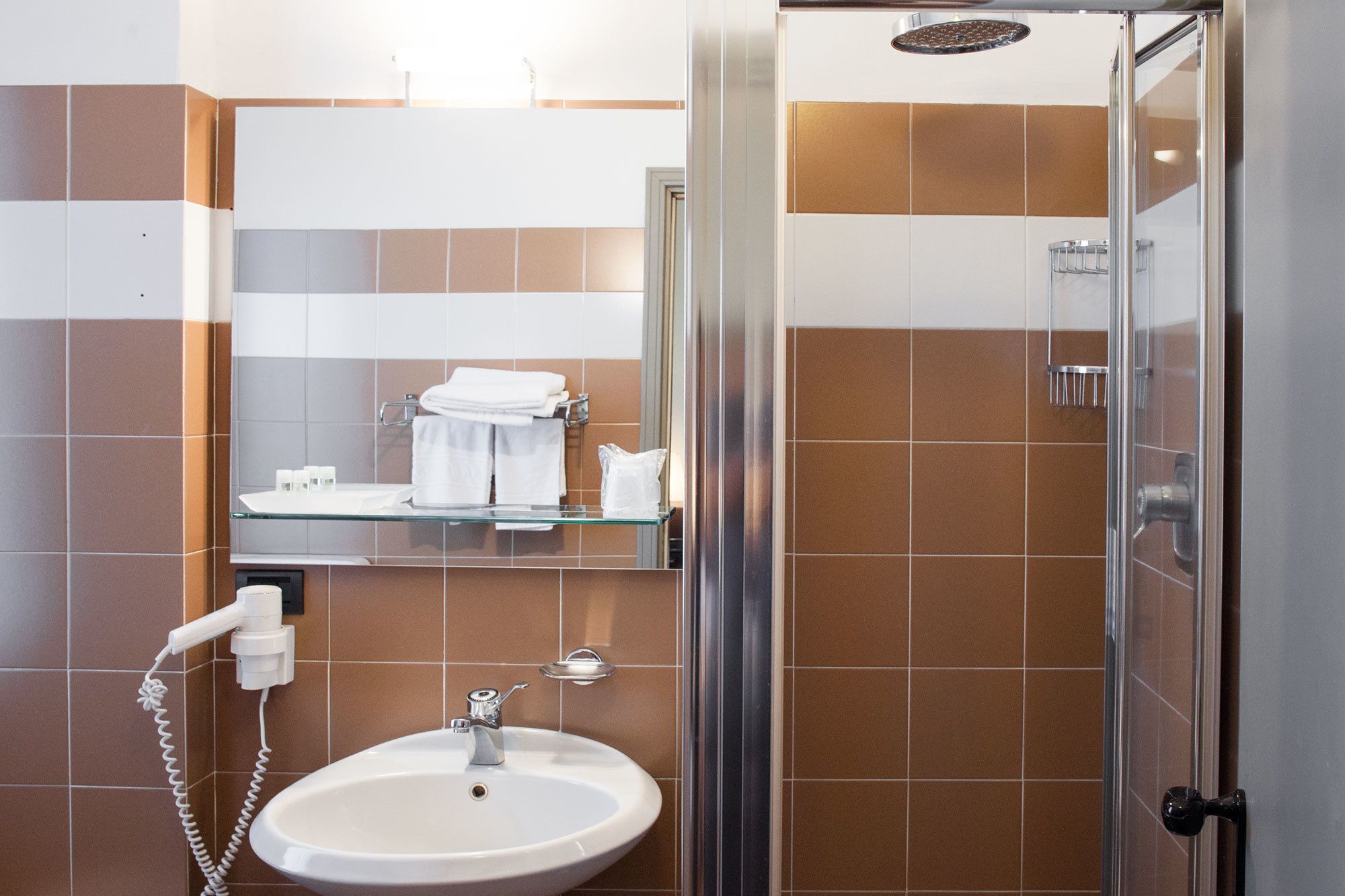 Une salle de bain avec une douche à parois de verre, un lavabo et un miroir au-dessus du lavabo.