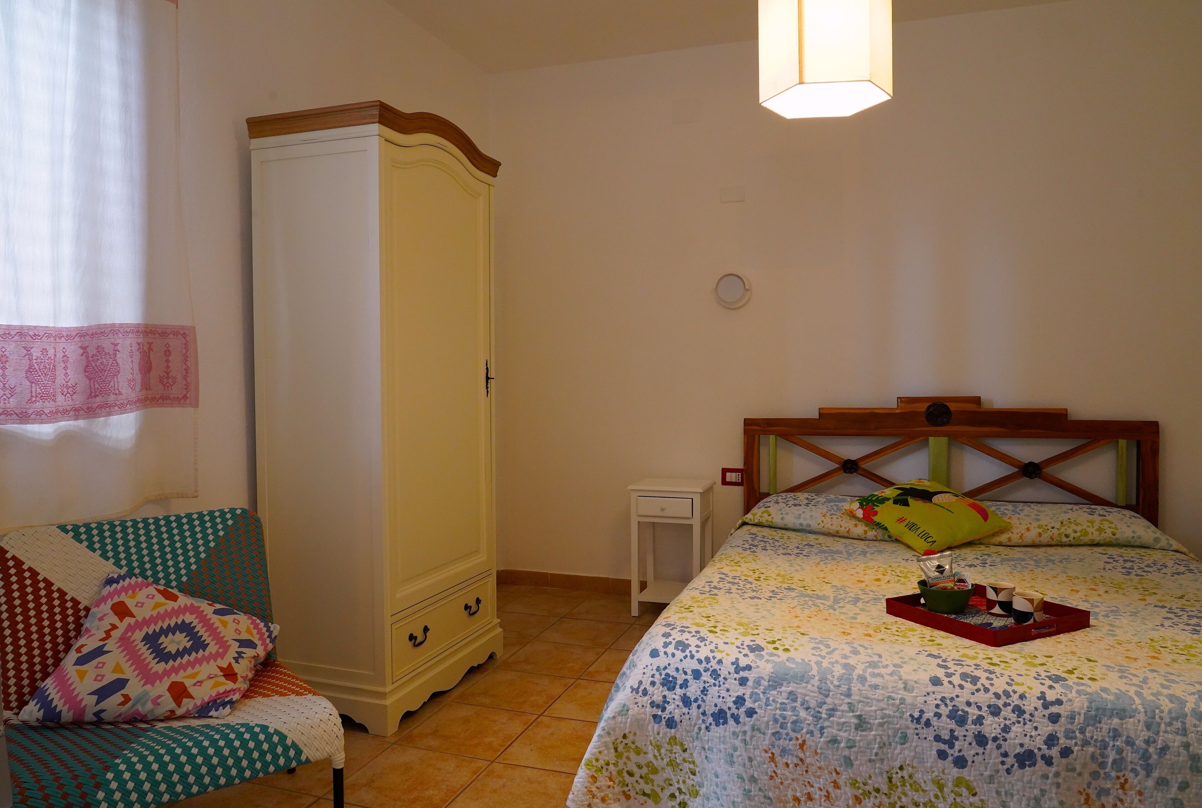 Un dormitorio con una cama, un armario, una silla y una mesita de noche.