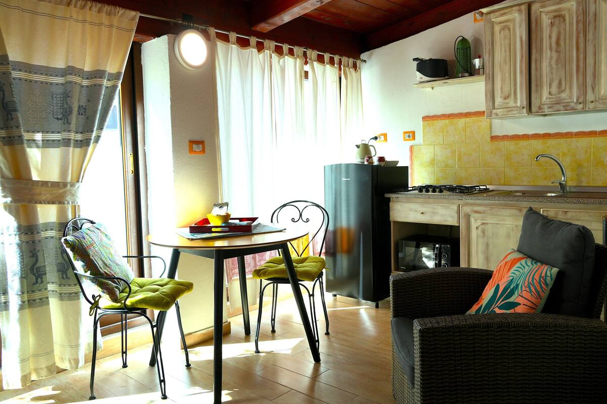 Un comedor con mesa y sillas, una cocina con armarios y un fregadero, y una sala de estar con sofá.