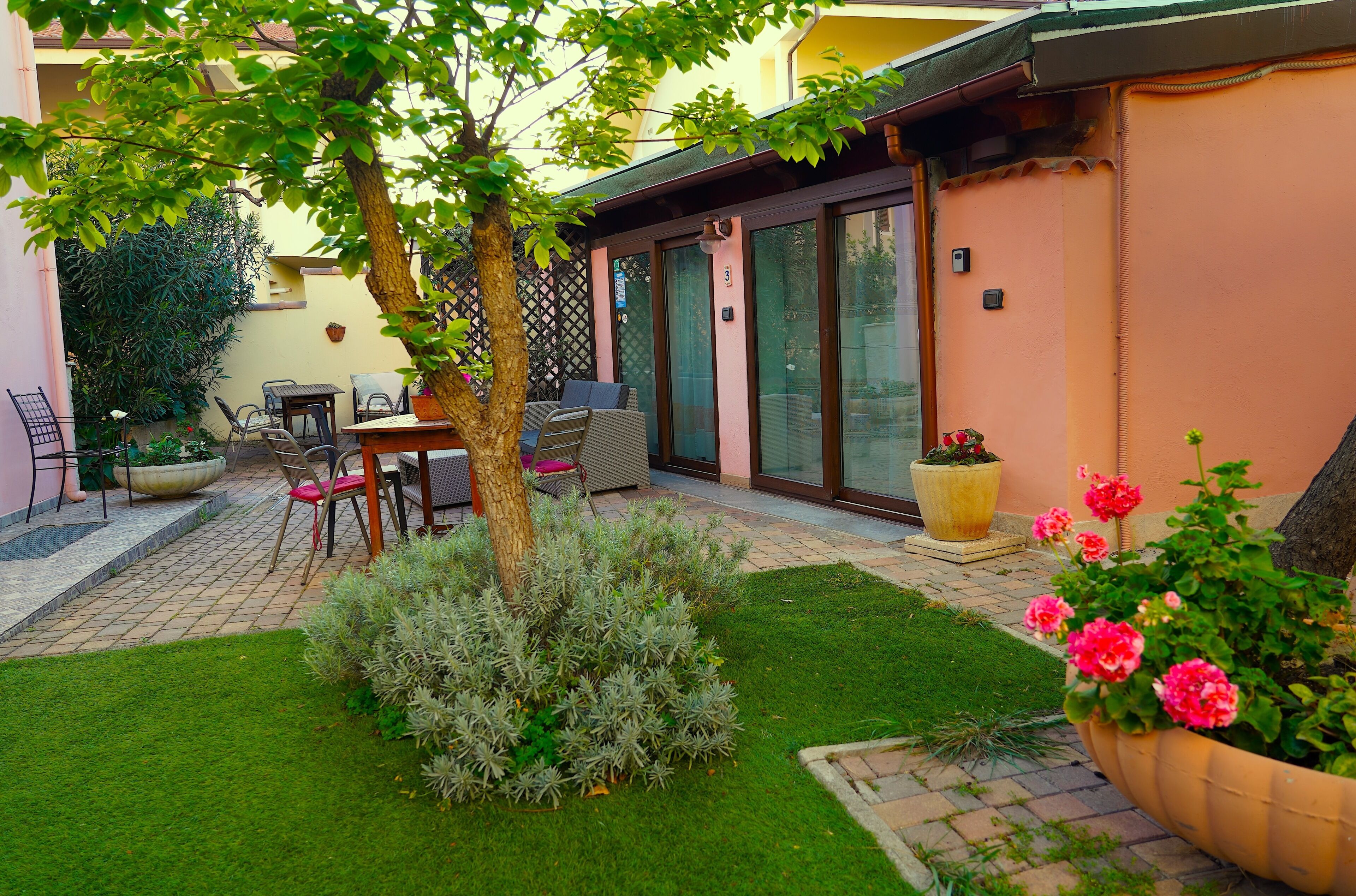 A patio with a table and chairs, a small lawn, and potted plants.