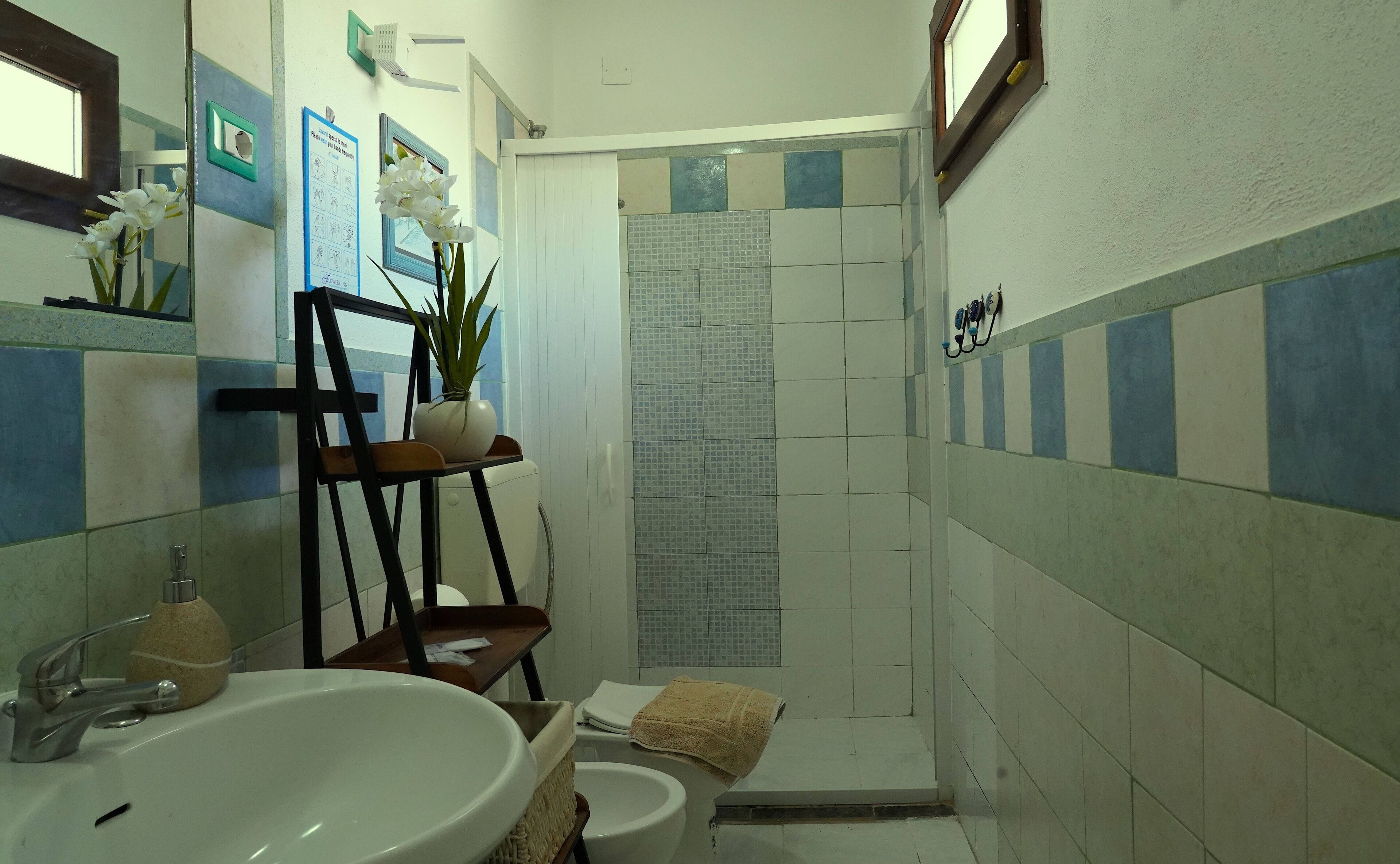 A bathroom with a sink, mirror, towel, shower curtain, and a potted plant.