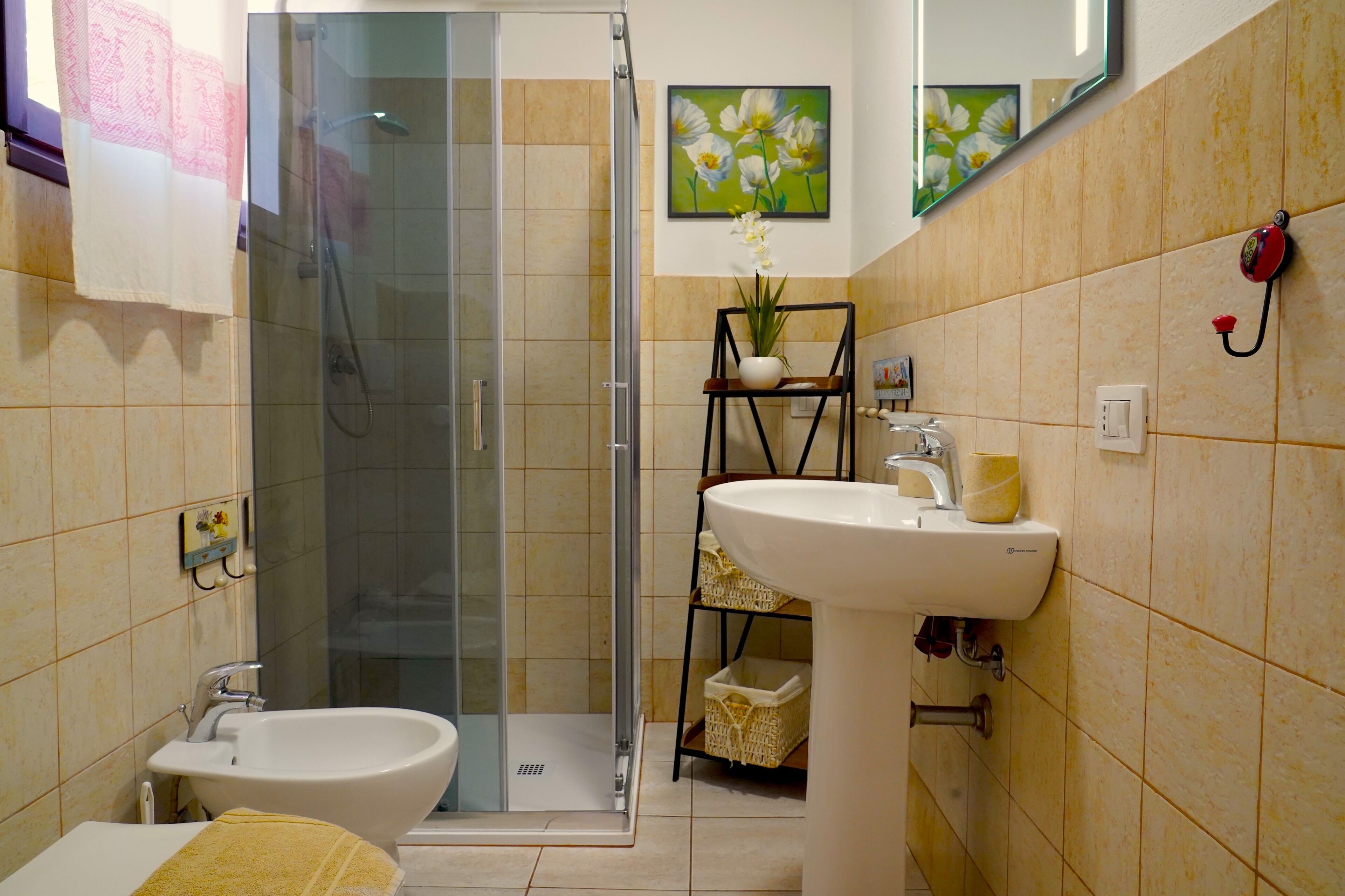 A bathroom with a glass-enclosed shower, a white sink, and a bidet.