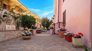 A narrow alley with potted flowers and a stone wall. - Flowery Inn Villa (Alghero)