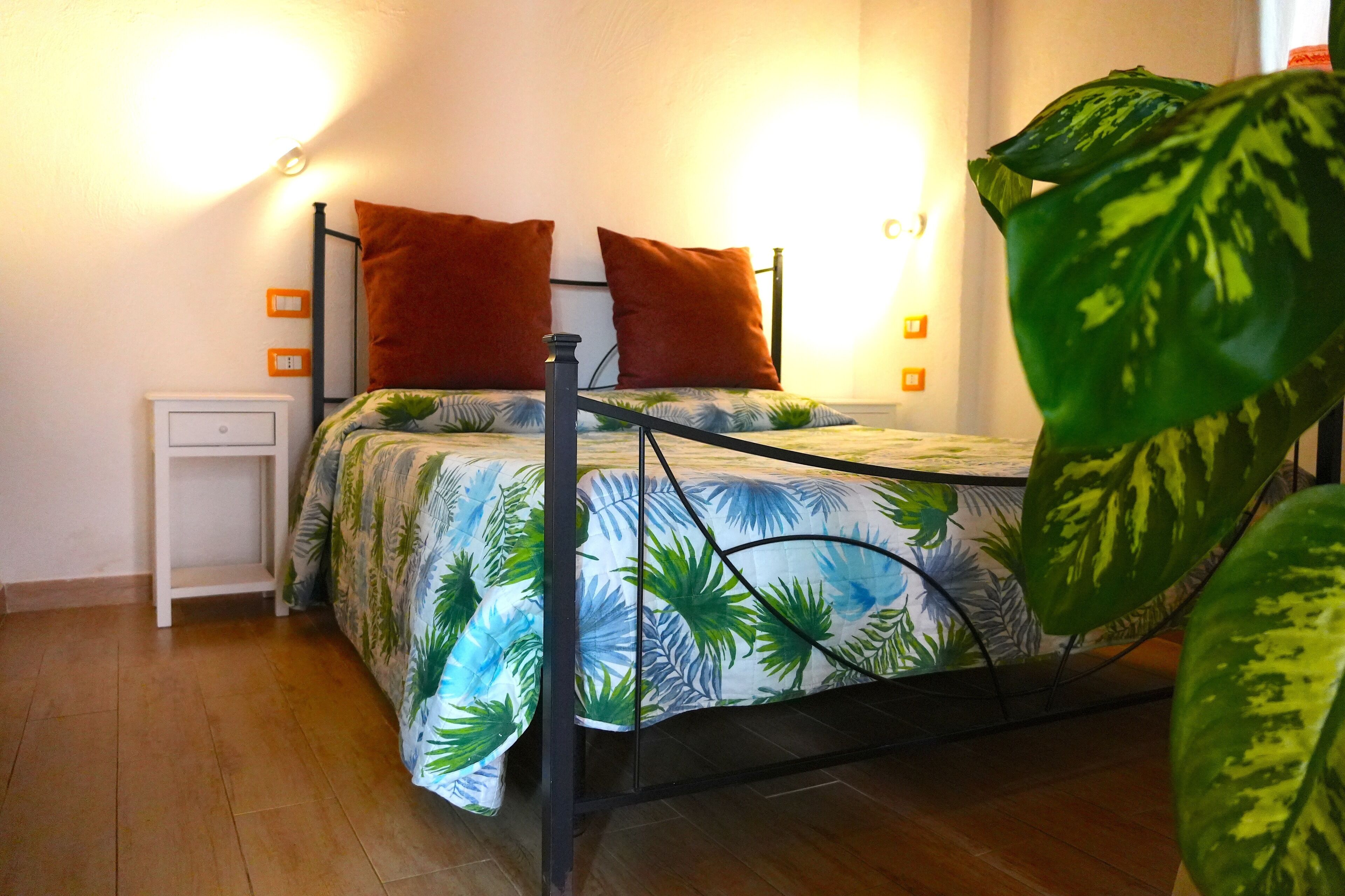 A bed with a metal frame, two pillows, a nightstand, and a wall-mounted light fixture.