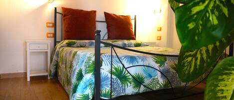 A bed with a metal frame, two pillows, a nightstand, and a wall-mounted light fixture.