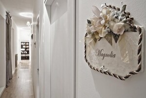 Un pasillo con un tapiz decorativo que dice "Magnolia" y una puerta que da a otra habitación.
