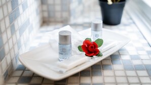 A tray with two bottles and a red rose on a tiled surface. - Fior di Loto Rooms (Cagliari)