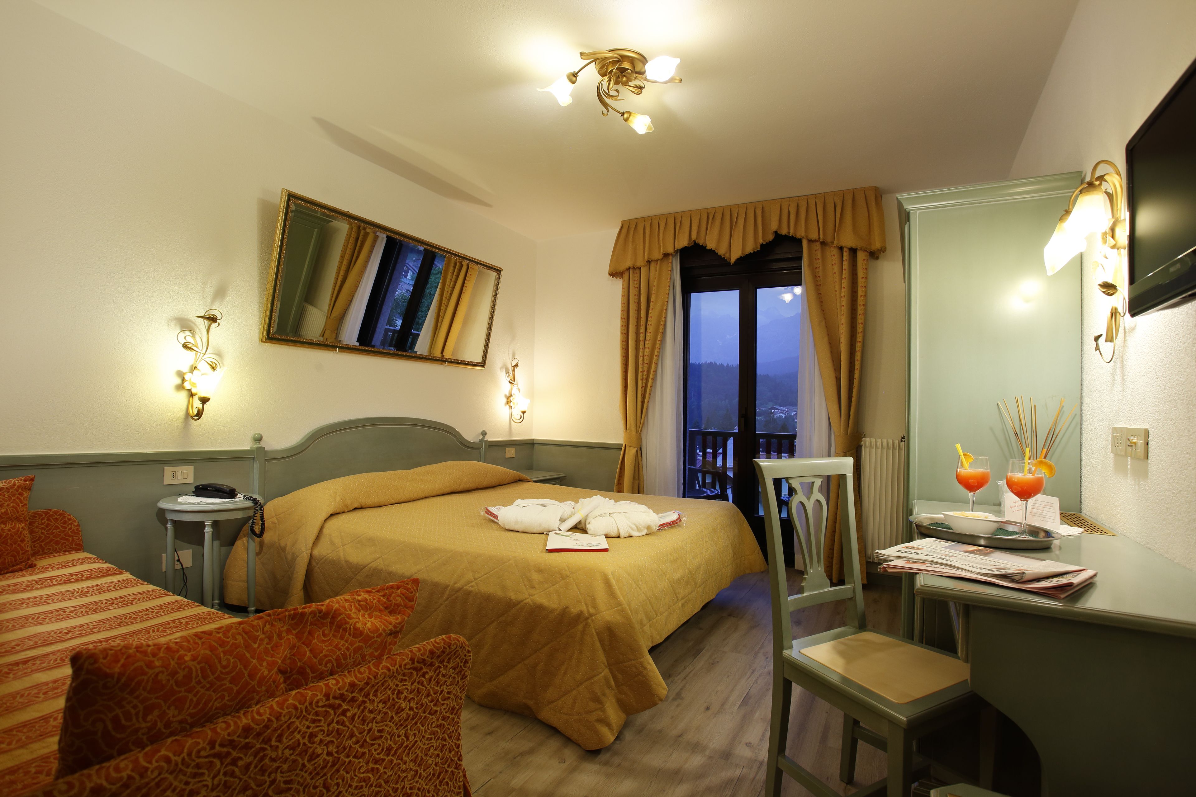 A hotel room with a bed, a desk, a chair, a television, and a window with curtains.