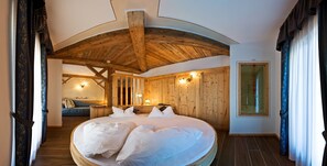 Un dormitorio acogedor con una cama grande, vigas de madera en el techo y un panel de pared de madera.