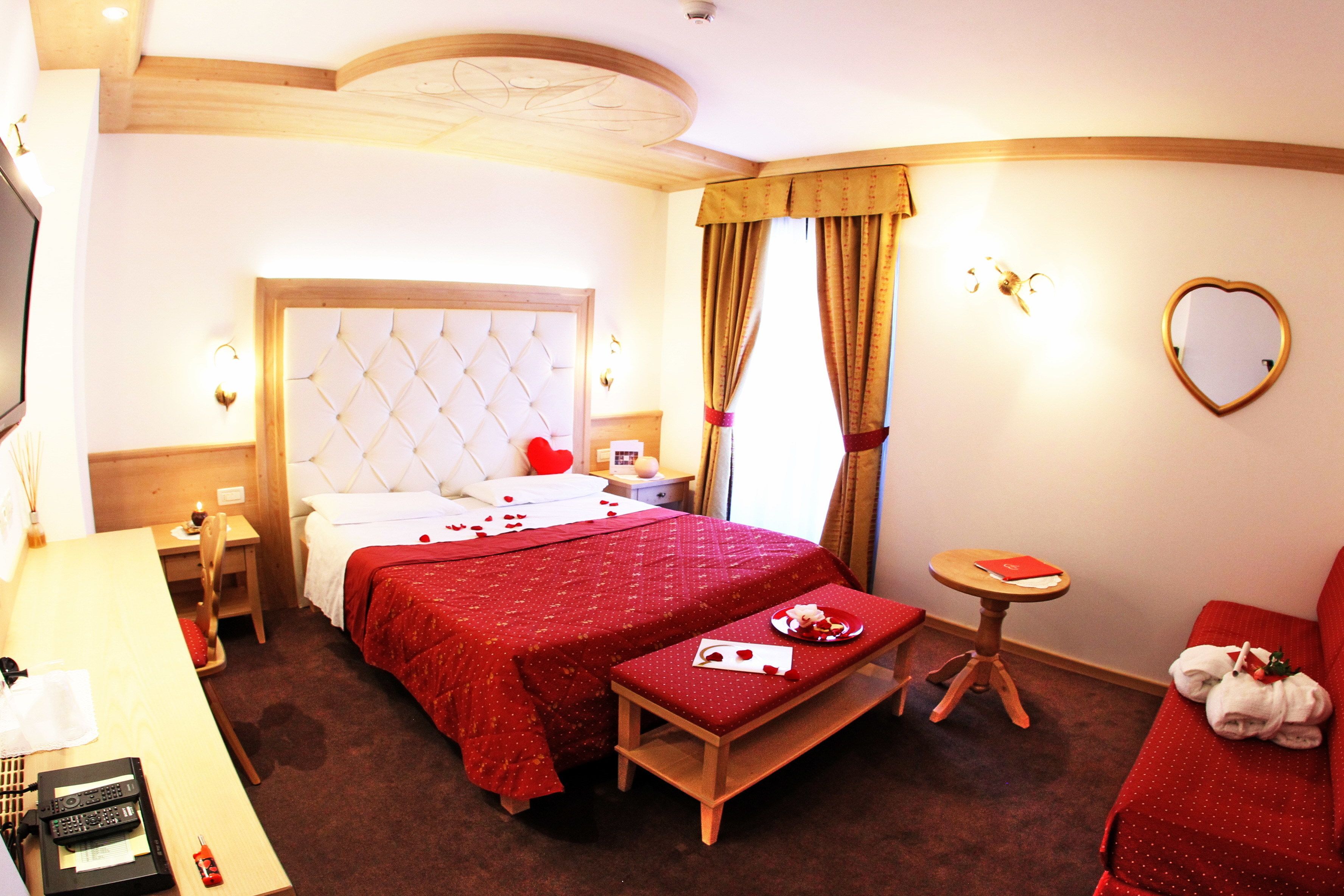 A hotel room with a large bed, a desk, a small table, and a sofa.