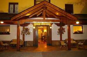 A hotel entrance with a wooden facade, a sign reading "Hotel Dal Bon," and wicker furniture outside. - Hotel Dal Bon (Andalo)