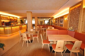 A restaurant with wooden tables and chairs, a bar area, and a seating area with booths.