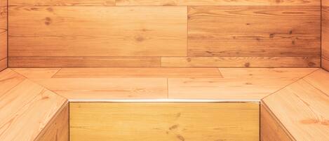 Una sauna de madera con un banco y otro banco en el suelo.