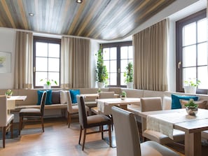 A spacious dining area with high ceilings, large windows, and comfortable seating.