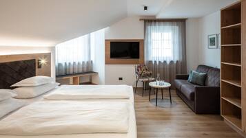 Una camera d'albergo con due letti, un divano, un tavolino, una televisione e una libreria.