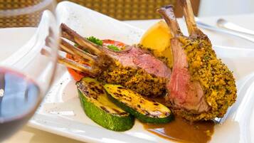 Un piatto con costolette di agnello, verdure grigliate e salsa.