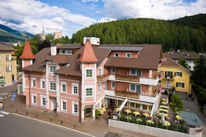 A multi-story hotel with a traditional European architectural style, featuring a prominent tower and a balcony with flower boxes.