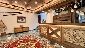 Quarto com teto de madeira, tapete estampado, banco de madeira e quadro pendurado na parede.
