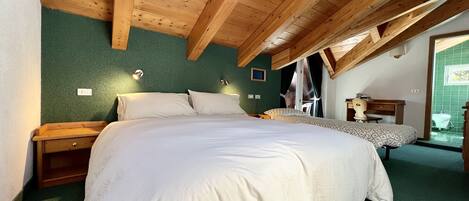 A bedroom with a wooden ceiling, a bed with white bedding, a nightstand, a desk with a chair, and a window with curtains.