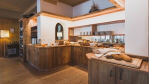 Uma cozinha de madeira com bancada para refeições, prateleiras com utensílios de cozinha e janela com vista.