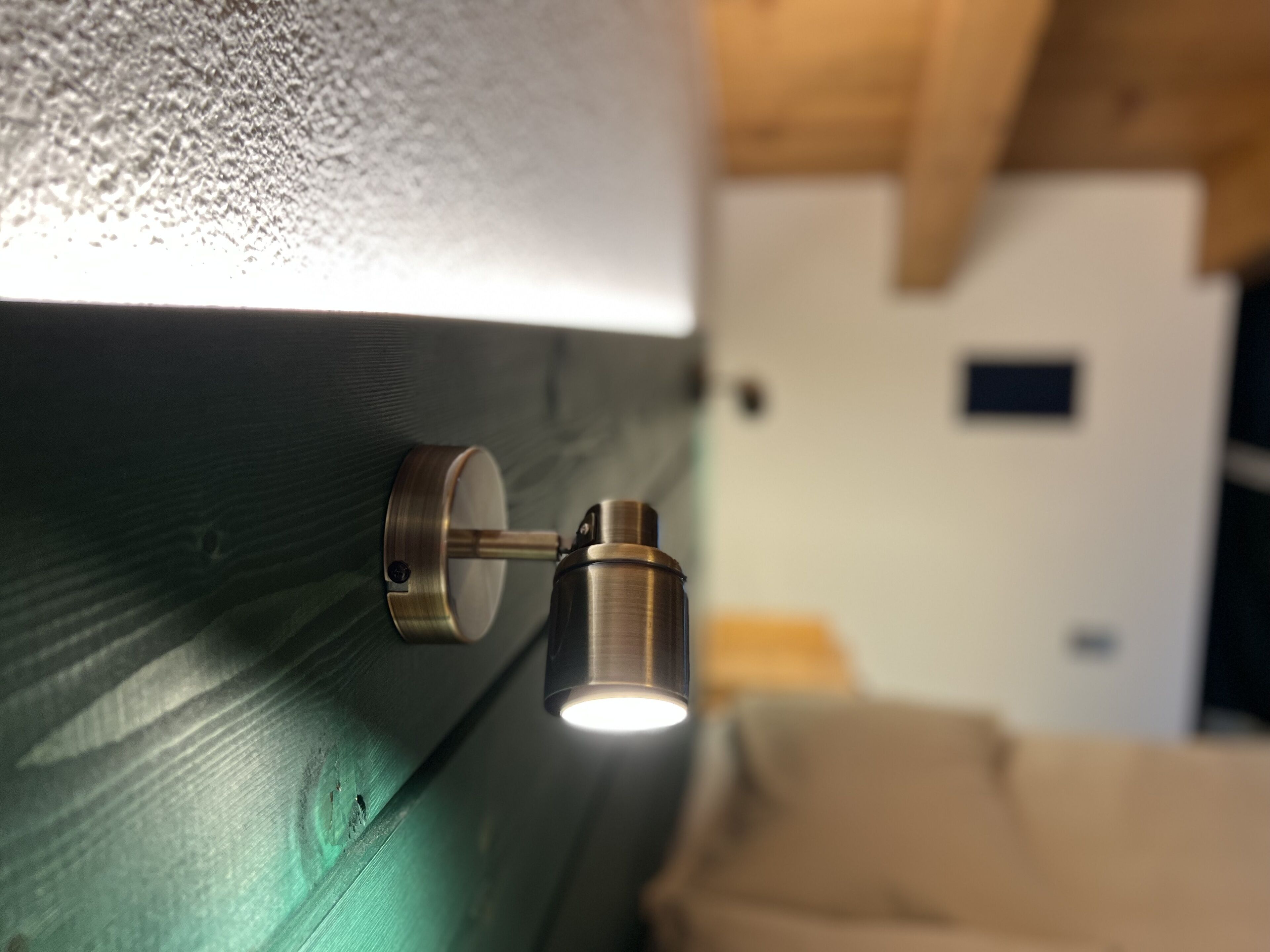 A close-up of a metallic light fixture attached to a textured wall.
