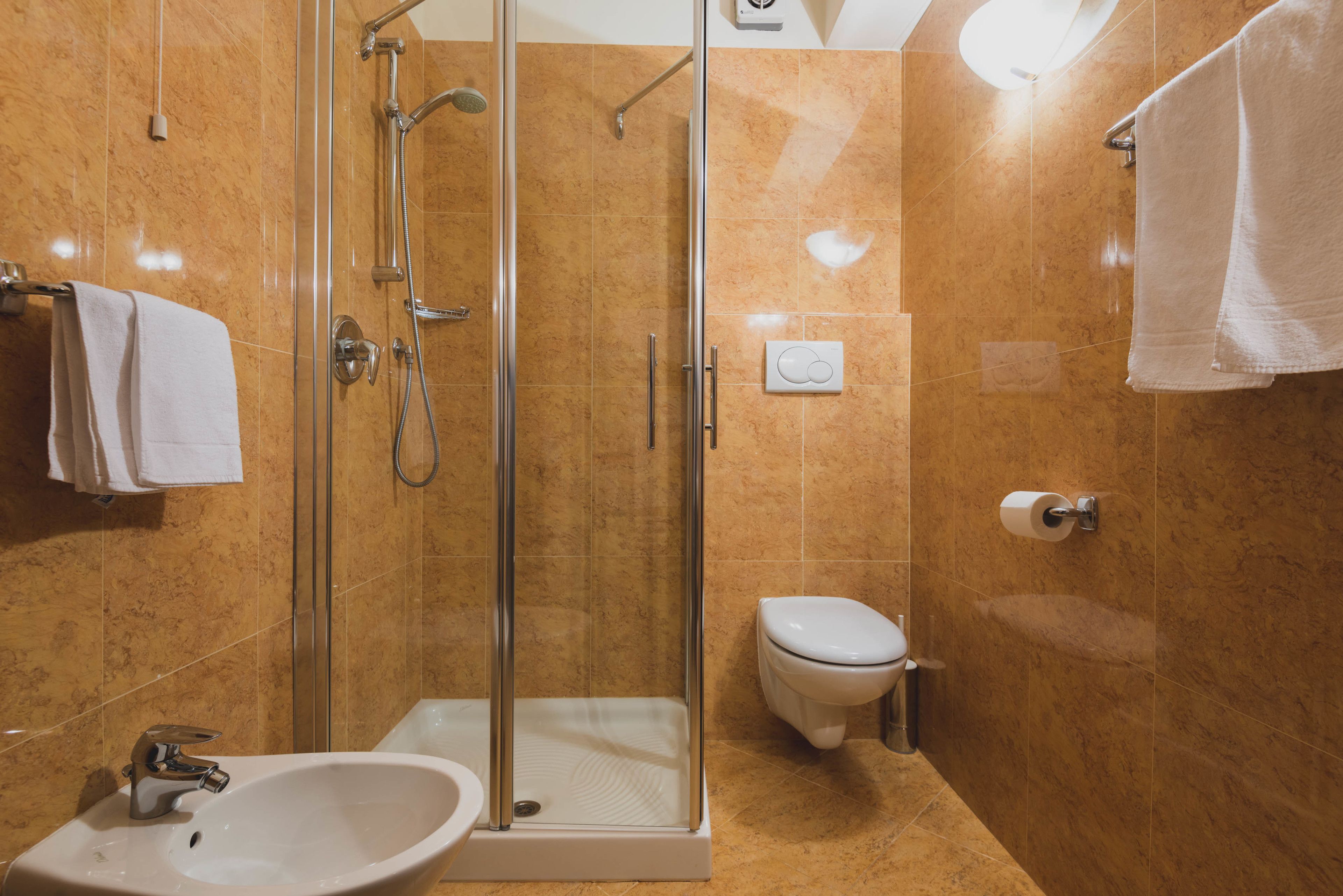 A modern bathroom with a glass-enclosed shower, a white sink, and a toilet.